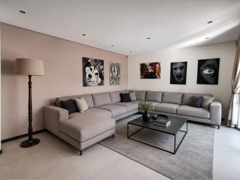 A well-maintained living room featuring neutral tiled flooring and recessed downlighting, creating a clean and modern atmosphere.