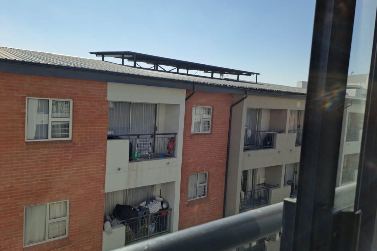 Exterior view of a multi-story apartment building featuring brick cladding, private balconies with metal railings, and sliding glass doors.