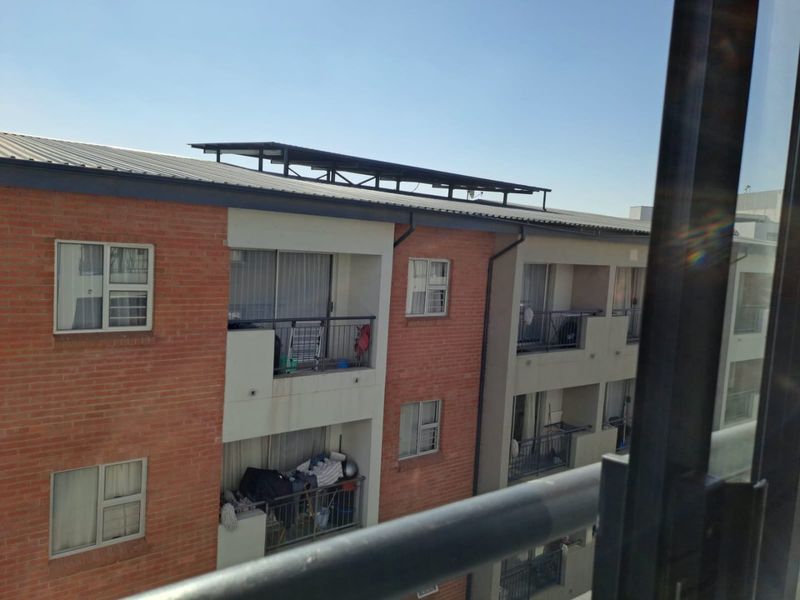 Exterior view of a multi-story apartment building featuring brick cladding, private balconies with metal railings, and sliding glass doors.