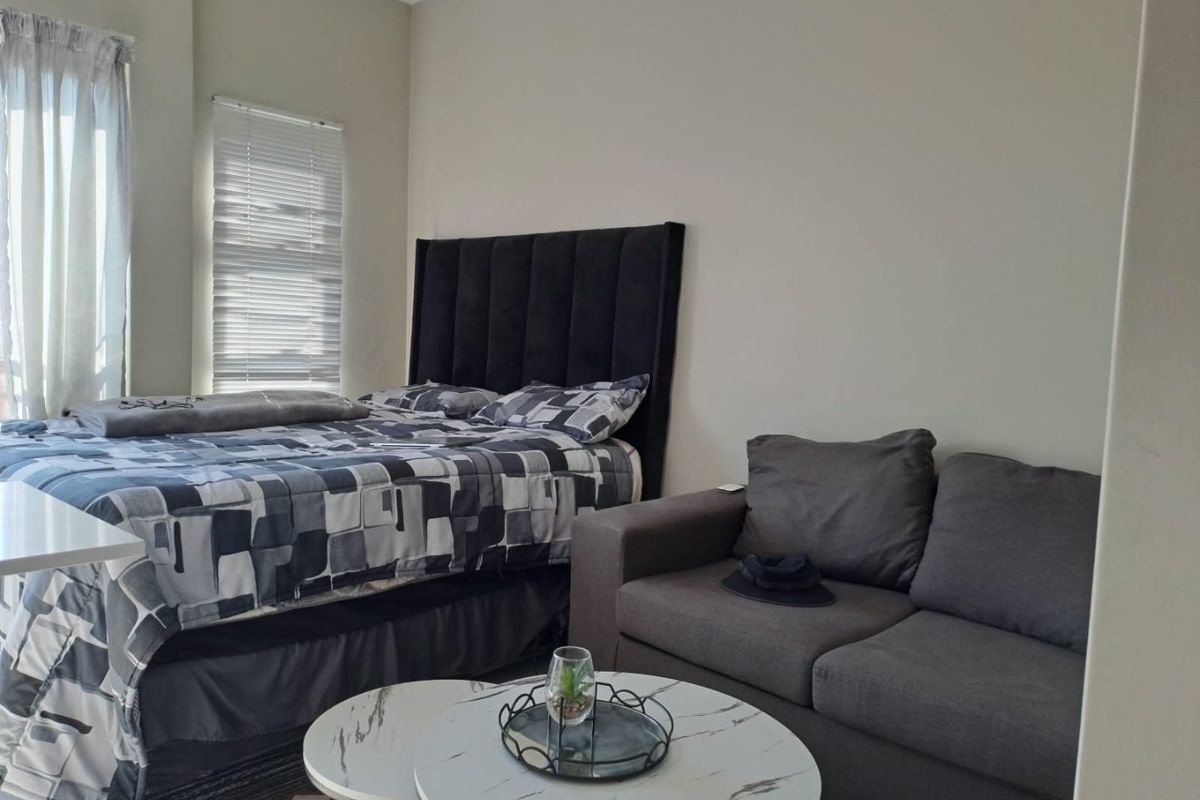 A well-maintained bedroom featuring neutral wall finishes, coving, and window treatments including venetian blinds and curtain tracks.
