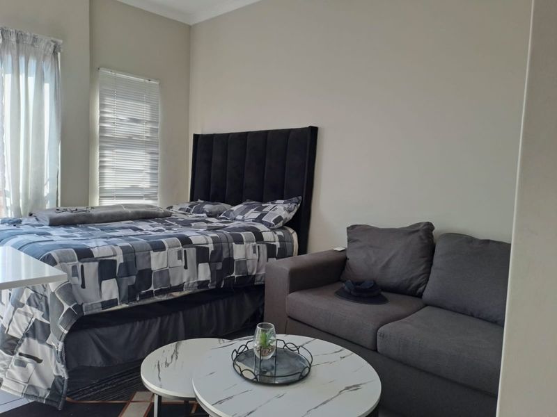 A well-maintained bedroom featuring neutral wall finishes, coving, and window treatments including venetian blinds and curtain tracks.