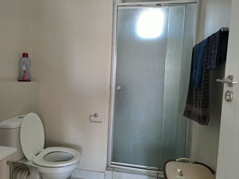 A functional bathroom featuring a shower enclosure and a standard toilet, providing essential sanitary facilities.