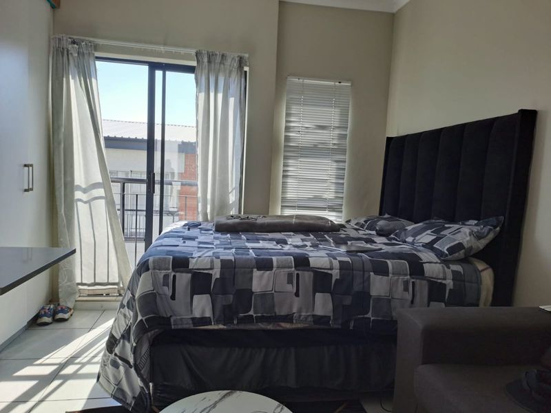A bedroom featuring tiled flooring, a sliding glass door leading to a balcony, and venetian blinds for natural light control.