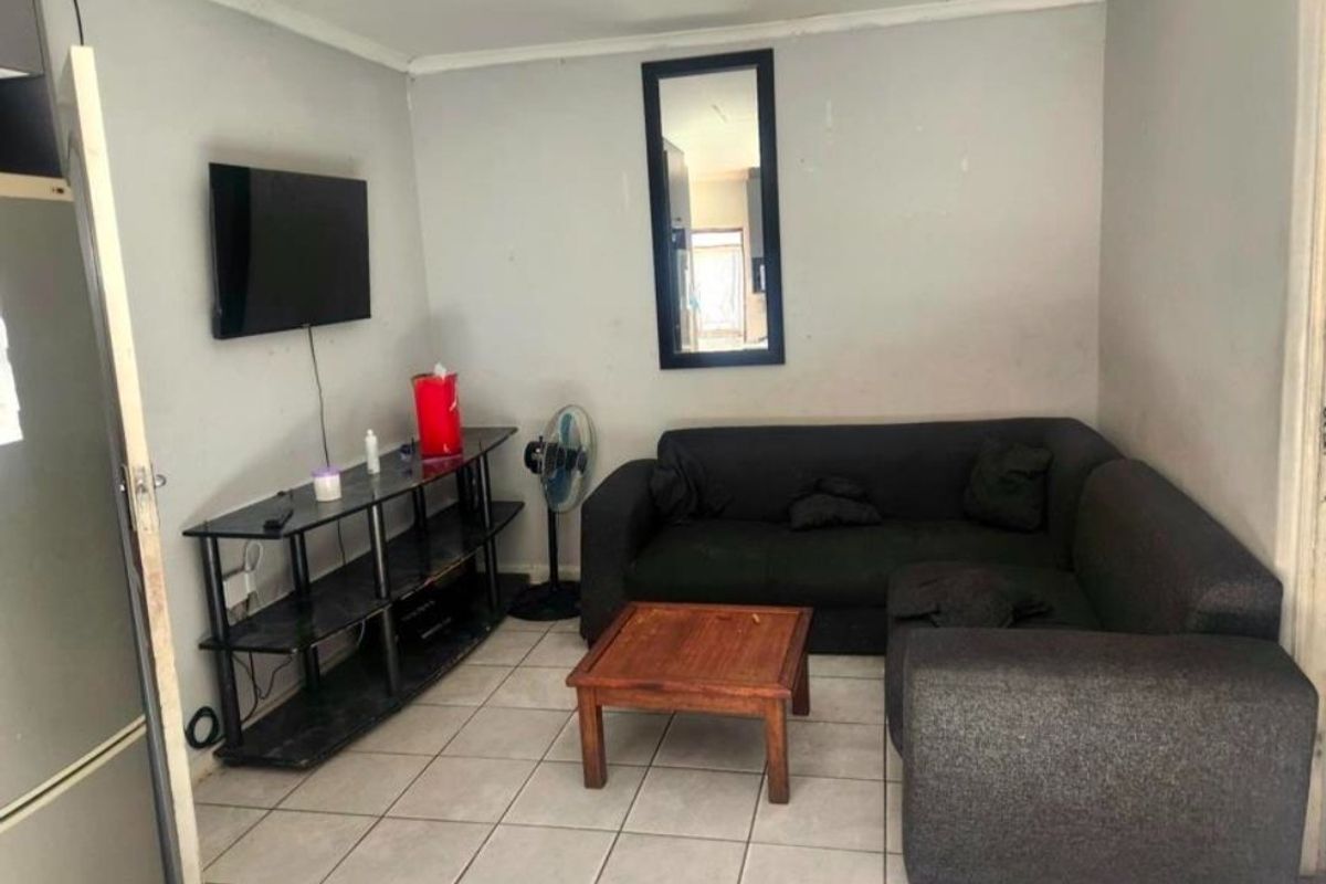 A compact living room featuring tiled flooring and neutral wall finishes, providing a functional space for relaxation.