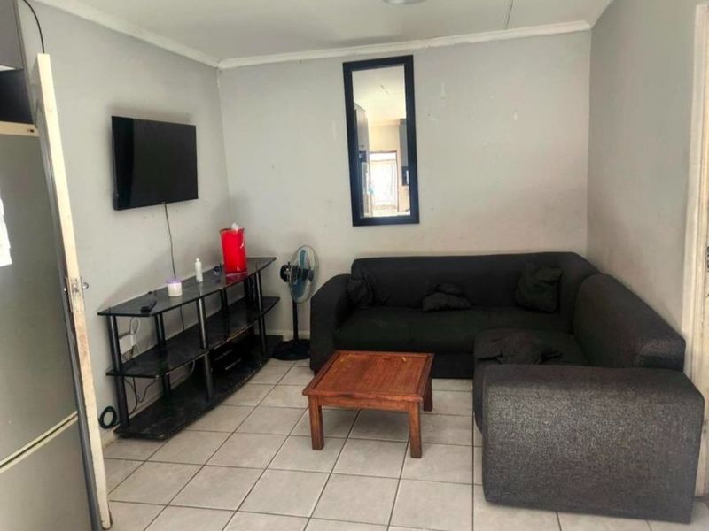 A compact living room featuring tiled flooring and neutral wall finishes, providing a functional space for relaxation.