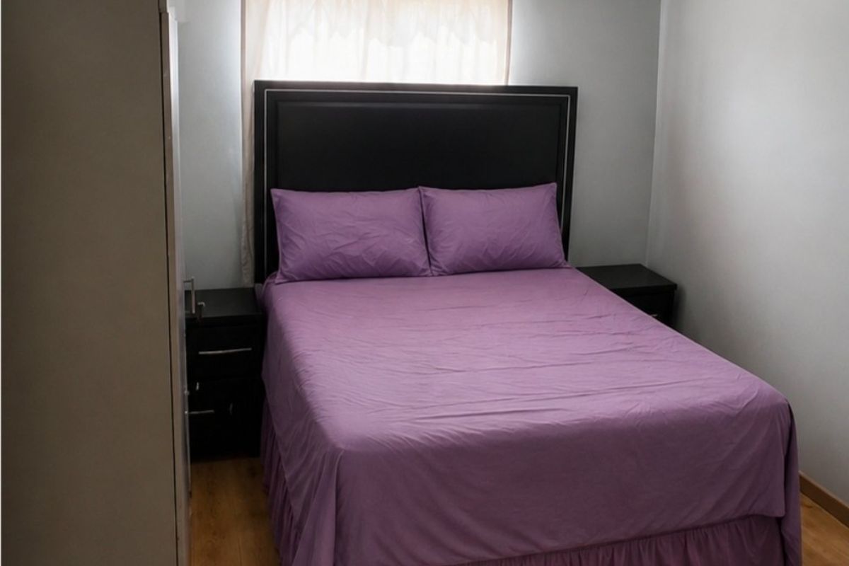 A functional bedroom featuring laminate flooring, neutral wall paint, and a coved ceiling.