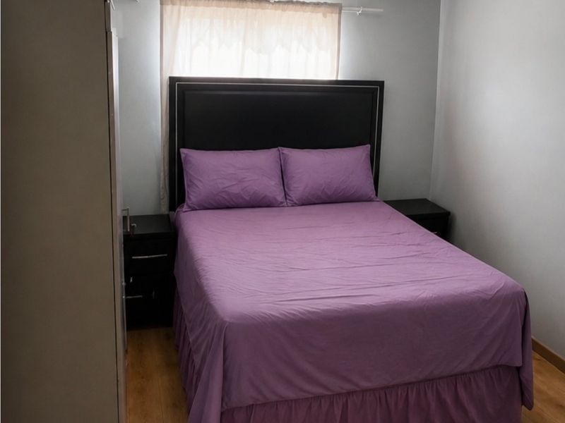 A functional bedroom featuring laminate flooring, neutral wall paint, and a coved ceiling.