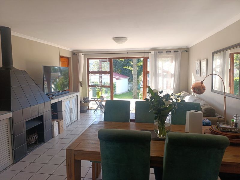 Open plan living and dining area featuring a tiled fireplace, ceramic flooring, and large sliding glass doors providing access to the rear garden.