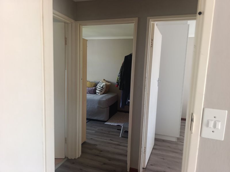 A view from the hallway looking into two adjacent bedrooms featuring laminate flooring and neutral wall finishes.