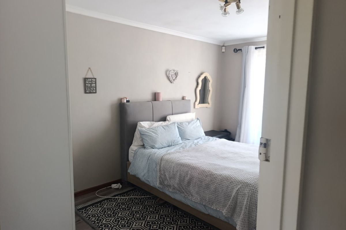 A neutrally painted bedroom featuring coving, a ceiling light fixture, and a curtain rod, viewed from the doorway.