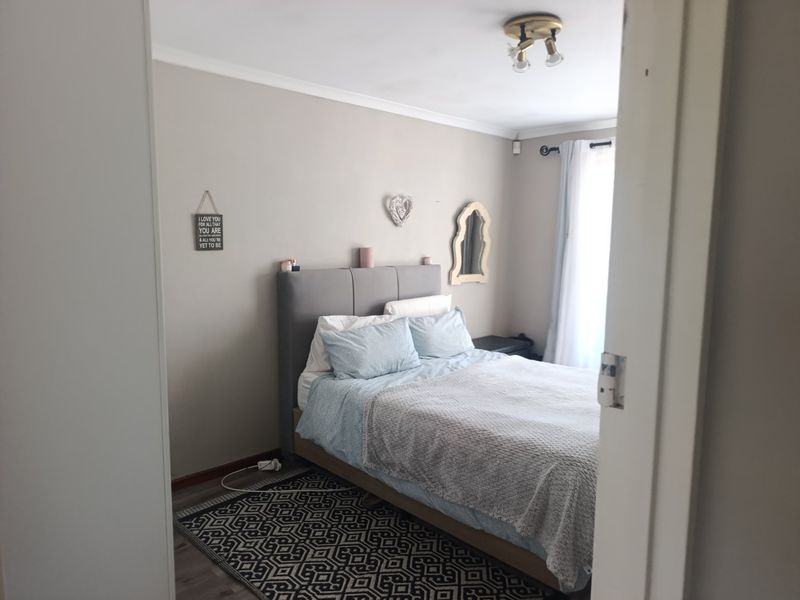 A neutrally painted bedroom featuring coving, a ceiling light fixture, and a curtain rod, viewed from the doorway.