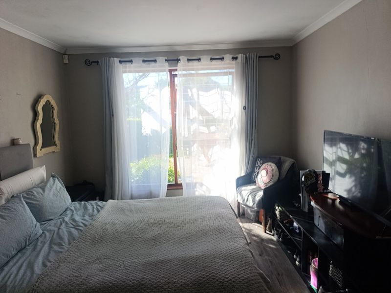 A bedroom featuring laminate flooring and a sliding glass door providing natural light and garden access.