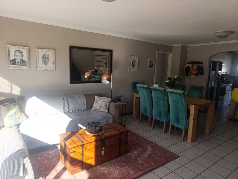 Open-plan living and dining area featuring tiled flooring and a neutral color palette, providing a functional space for relaxation and meals.