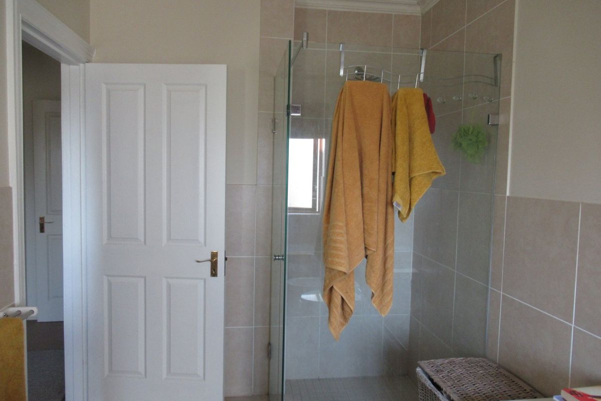 A clean bathroom featuring a glass-enclosed shower, neutral wall tiling, and classic panel door detailing.