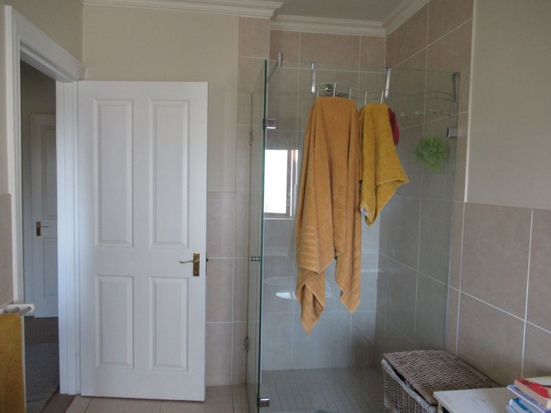 A clean bathroom featuring a glass-enclosed shower, neutral wall tiling, and classic panel door detailing.