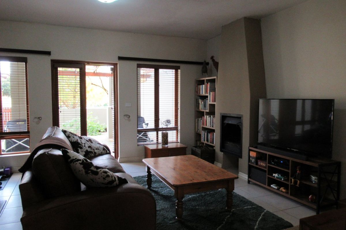 A comfortable living room featuring a built-in fireplace, tiled flooring, and large windows with sliding door access to the outdoor patio area.