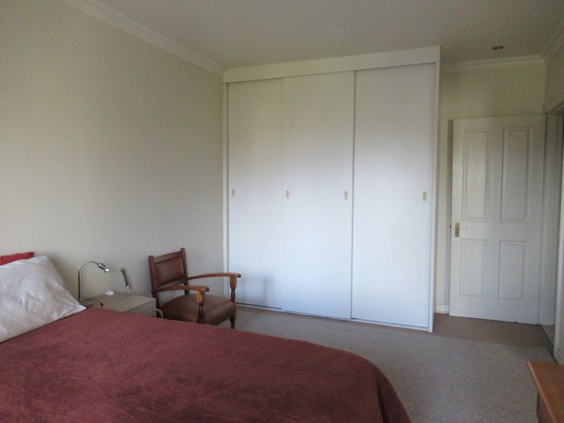 A bedroom featuring neutral walls, carpeted flooring, and a large built-in sliding door wardrobe with integrated storage.