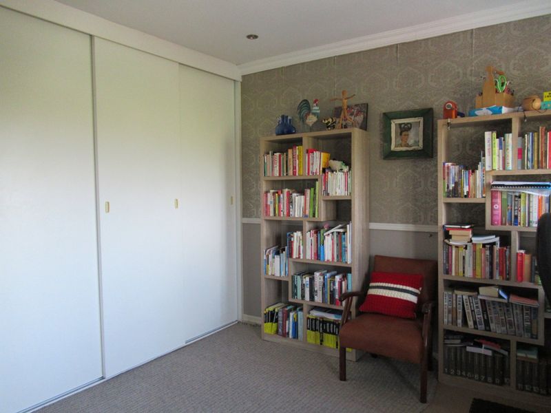 A bedroom featuring built-in sliding door wardrobes, patterned wallpaper, and recessed downlighting.