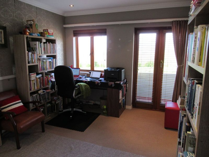 A functional home office featuring carpeted flooring, recessed lighting, and direct access to an outdoor area through double french doors.