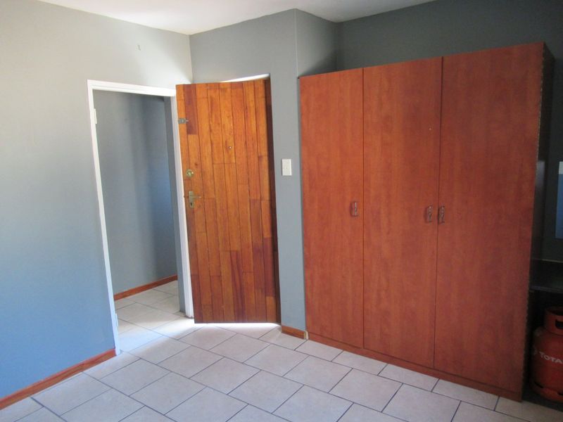 A vacant bedroom featuring tiled flooring, a built-in wooden wardrobe, and a timber entrance door.