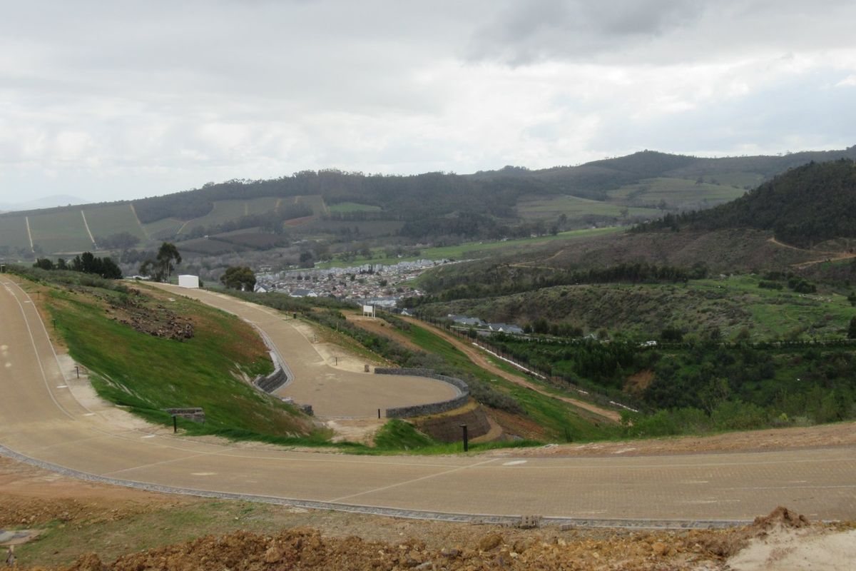An elevated view of a residential development site featuring paved roads, retaining walls, and scenic mountain landscape views.