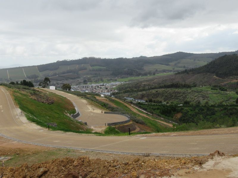 An elevated view of a residential development site featuring paved roads, retaining walls, and scenic mountain landscape views.