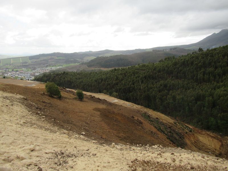 A wide-angle view of the sloped residential land featuring natural vegetation and expansive mountain scenery in the background.