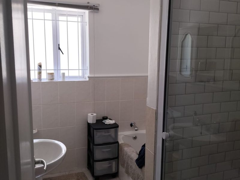 A functional bathroom featuring a pedestal basin, bathtub, and separate shower enclosure with subway tile finishes and an extractor fan.