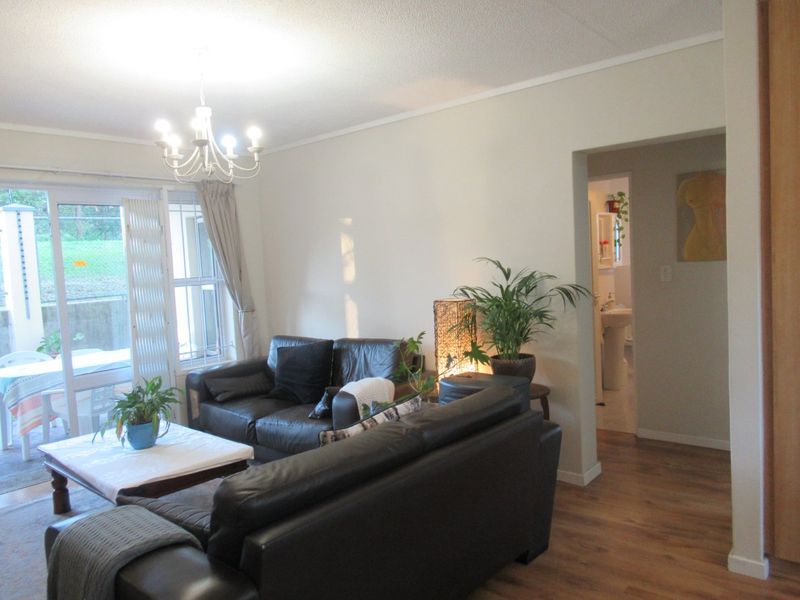 A living room featuring laminate flooring, a coved ceiling, and a sliding glass door providing access to an outdoor patio area.