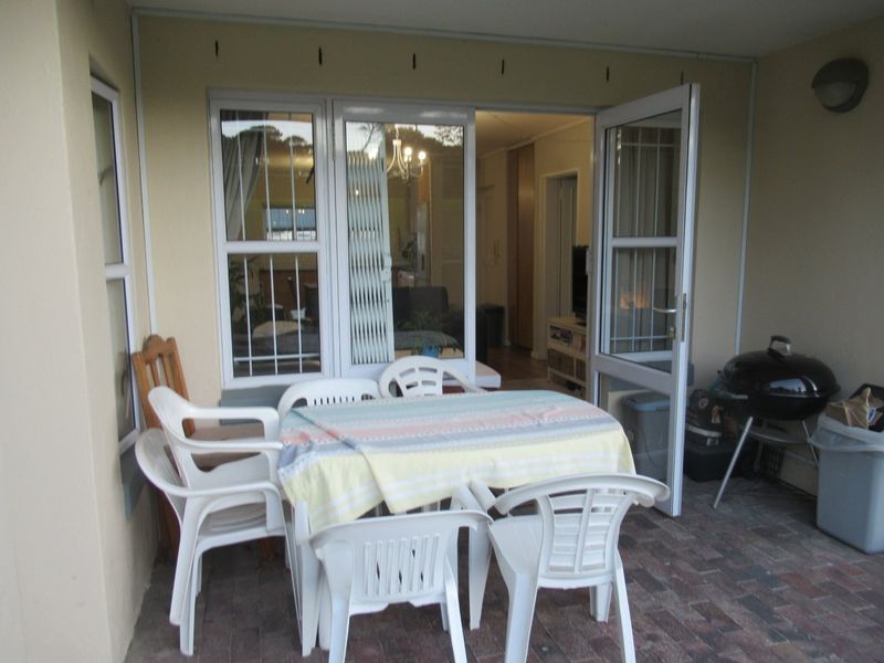 A covered patio area featuring paved flooring and direct access to the interior living space through glass sliding doors.