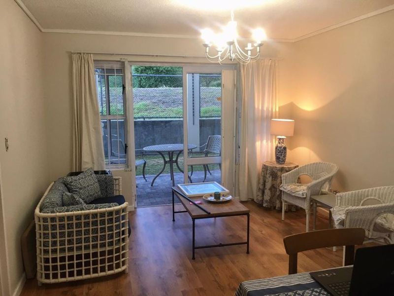 A living room featuring laminate flooring and a sliding glass door that provides access to an outdoor patio area.