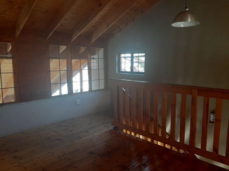 An open landing area featuring timber flooring, a vaulted wooden ceiling, and a traditional timber balustrade overlooking the staircase.