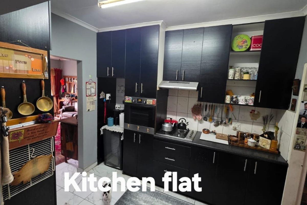 A functional kitchen featuring dark cabinetry, built-in oven, gas hob, extractor fan, and tiled flooring with a tiled backsplash.