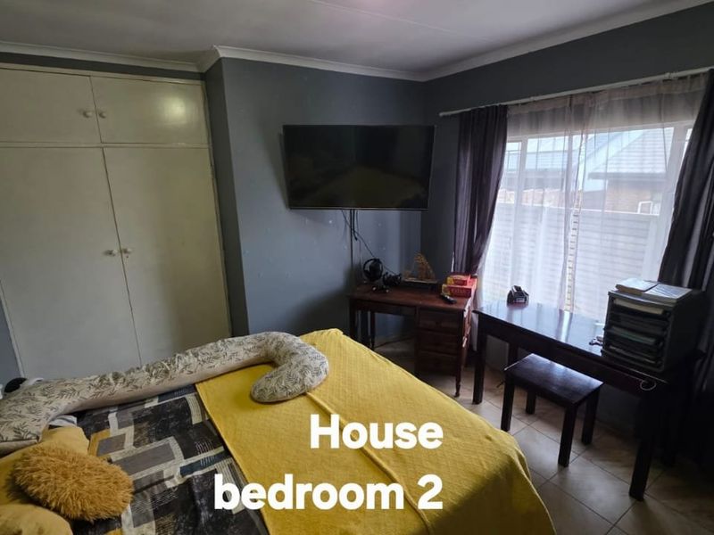 A bedroom featuring built-in cupboards, tiled flooring, and a window with curtaining.