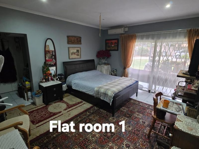 A bedroom featuring tiled flooring, an air conditioning unit, and a sliding glass door with a security gate providing access to the exterior.