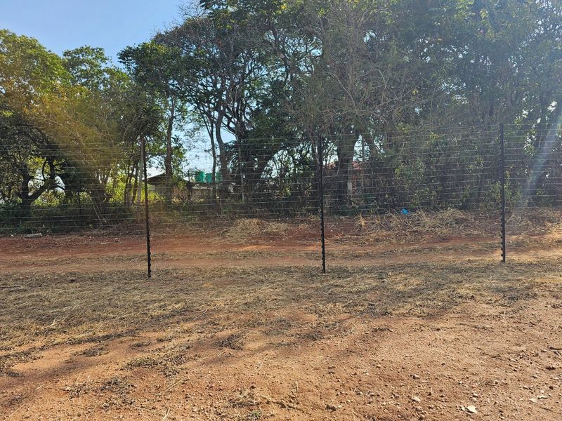 A view of the property boundary featuring installed electric fencing set against a backdrop of mature trees and natural vegetation.