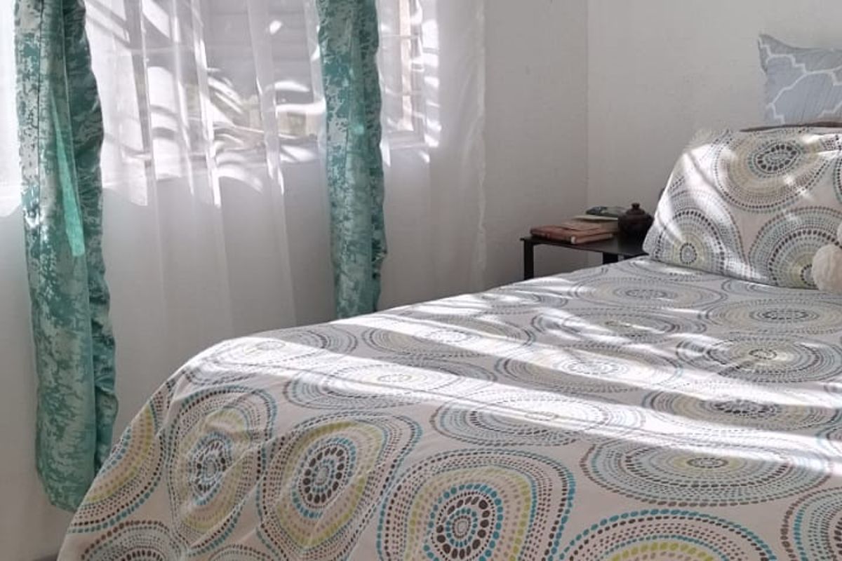 A bedroom featuring parquet flooring and natural light from a window.