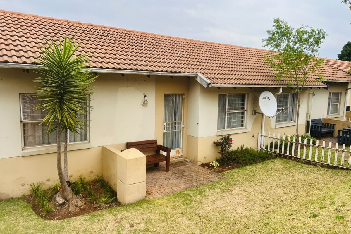Rear view of the apartment featuring a brick paved patio, terracotta roof tiles, and a small garden area with a picket fence.