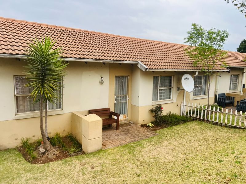 Rear view of the apartment featuring a brick paved patio, terracotta roof tiles, and a small garden area with a picket fence.