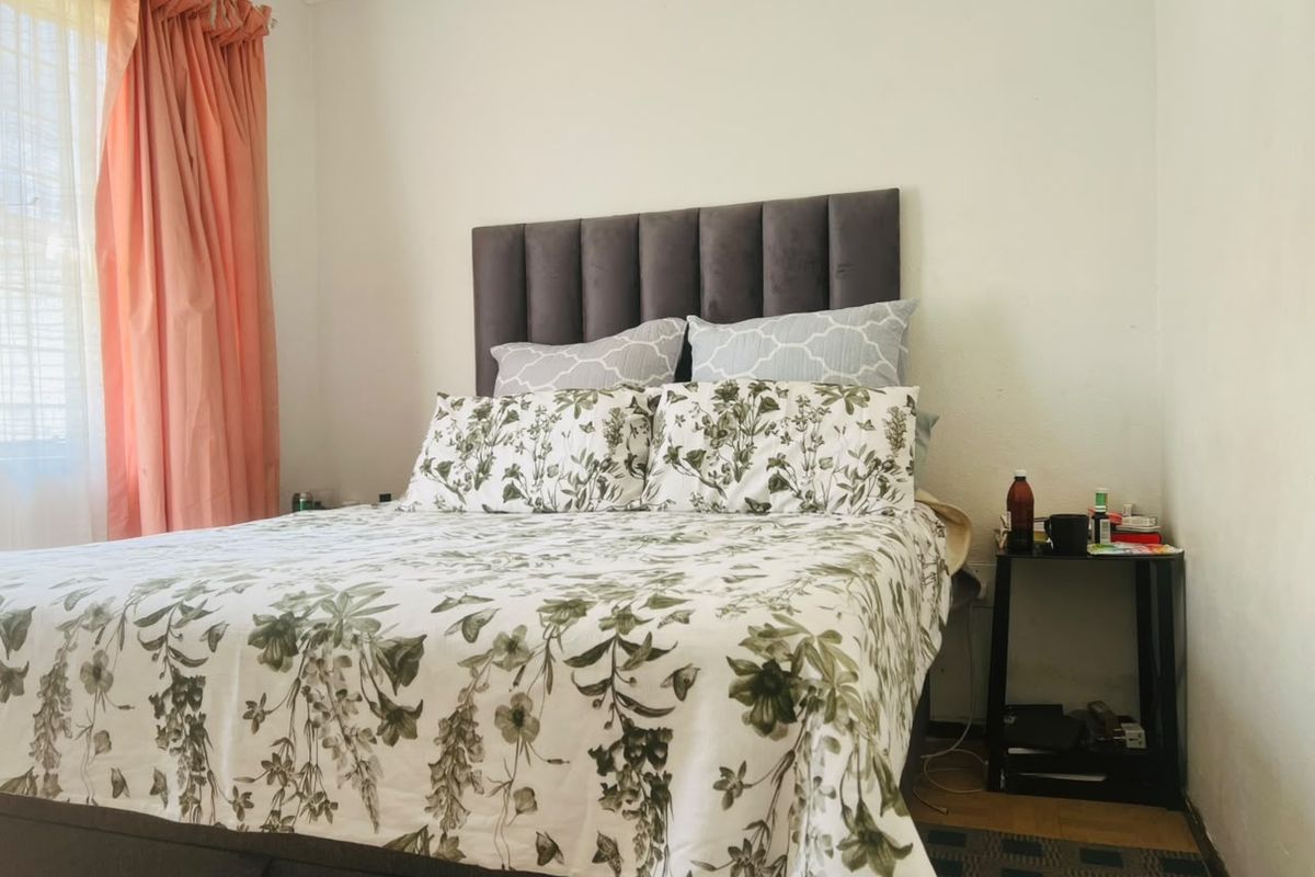 A bedroom featuring a grey upholstered headboard and neutral wall finishes, providing a comfortable and functional sleeping space.