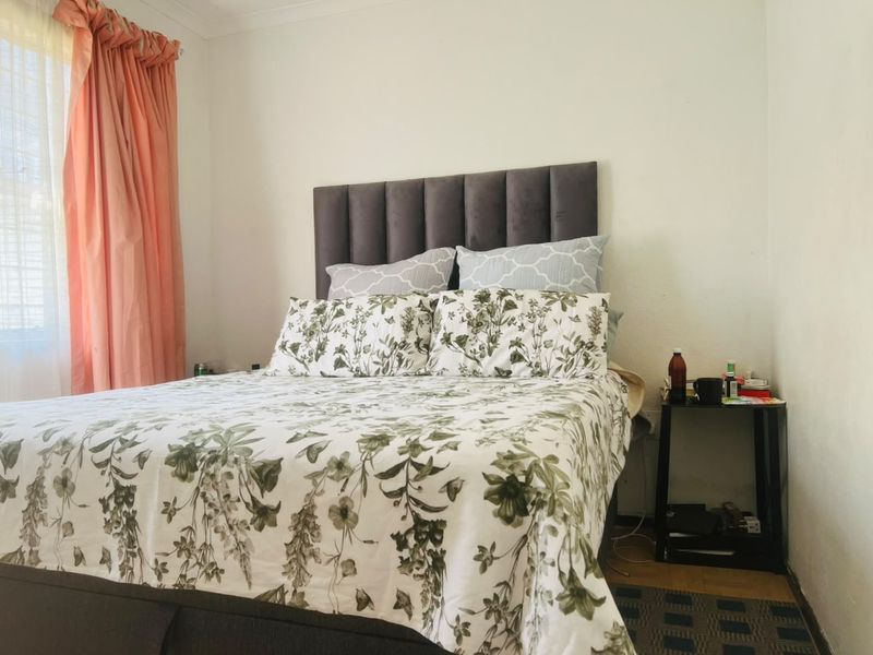 A bedroom featuring a grey upholstered headboard and neutral wall finishes, providing a comfortable and functional sleeping space.