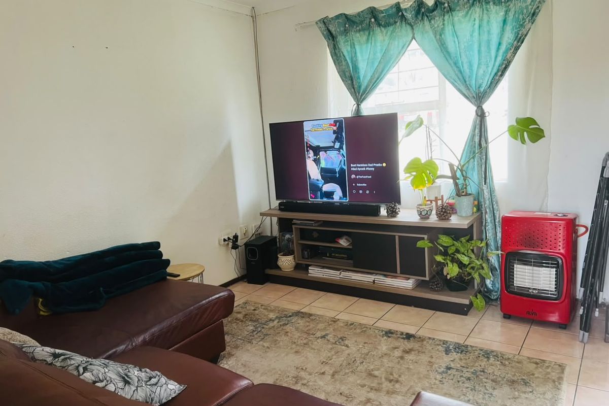 A living room area featuring tiled flooring and a window, providing a functional space for relaxation.
