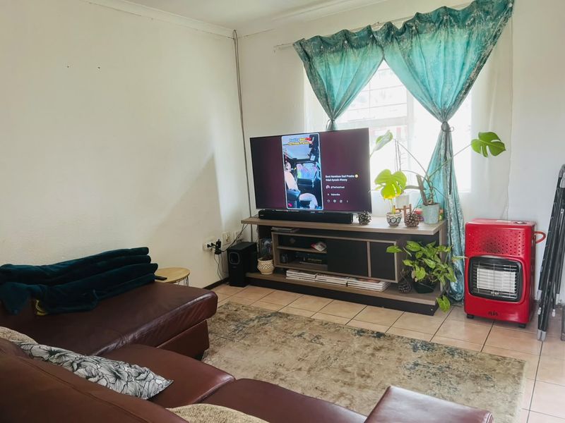 A living room area featuring tiled flooring and a window, providing a functional space for relaxation.
