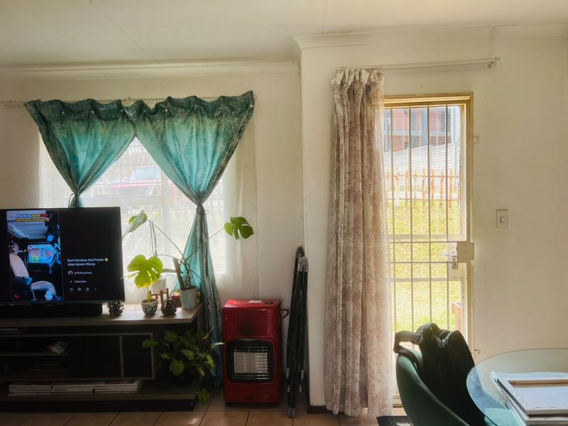 A living room area featuring tiled flooring, a security gate leading to the exterior, and curtain rails.