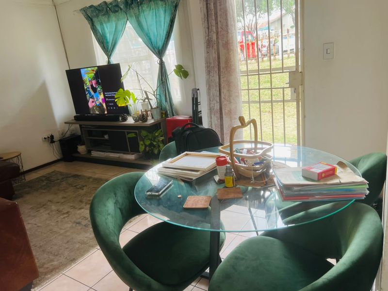 A living area featuring tiled flooring and a security gate leading to the exterior, providing natural light and access to the outdoors.