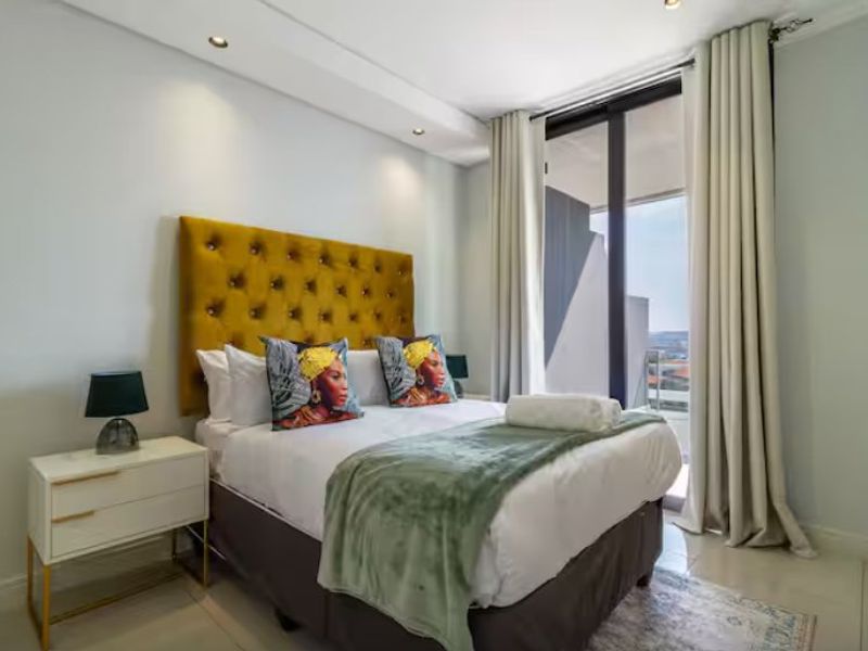 A well-lit bedroom featuring tiled flooring, recessed ceiling lighting, and a sliding glass door providing access to an outdoor area.