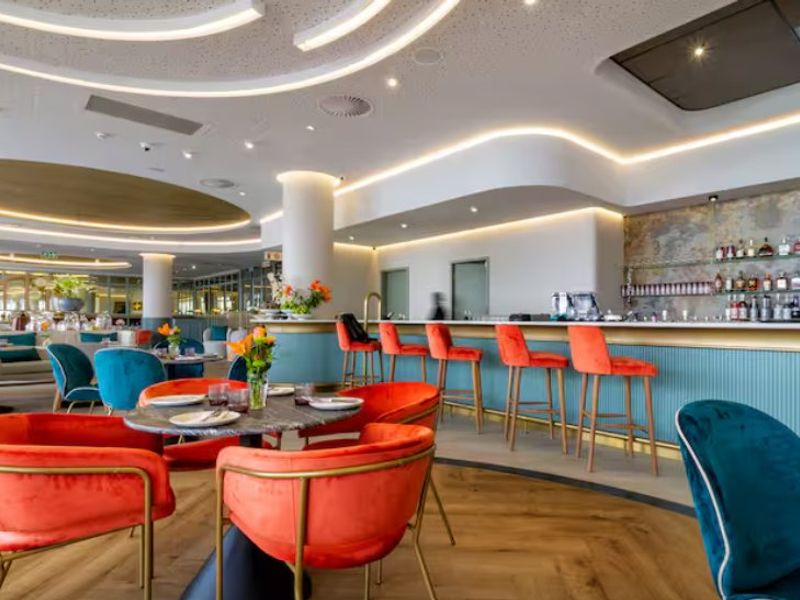 A modern, high-end bar area featuring a built-in counter, sophisticated recessed and cove lighting, and premium hardwood flooring in a well-maintained commercial space.