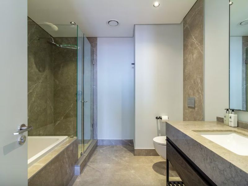 Modern bathroom featuring high-end stone finishes, a glass-enclosed shower, a built-in bathtub, and a sleek vanity with an undermount sink.