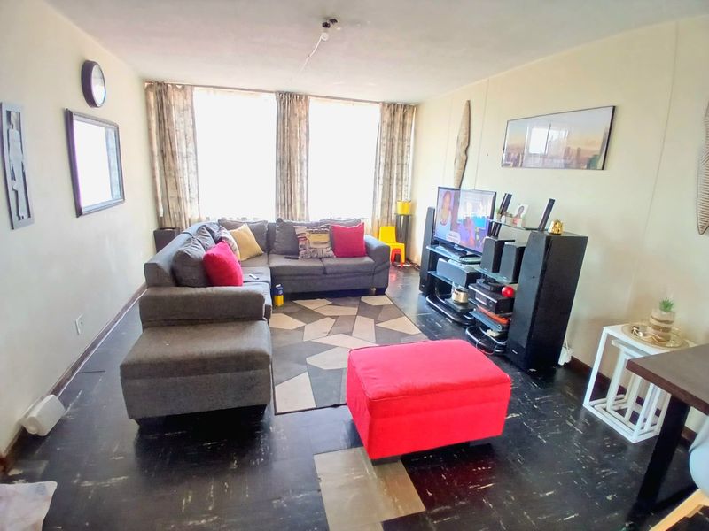 A living room featuring large windows for natural light and dark vinyl flooring, offering a blank canvas for potential interior updates.