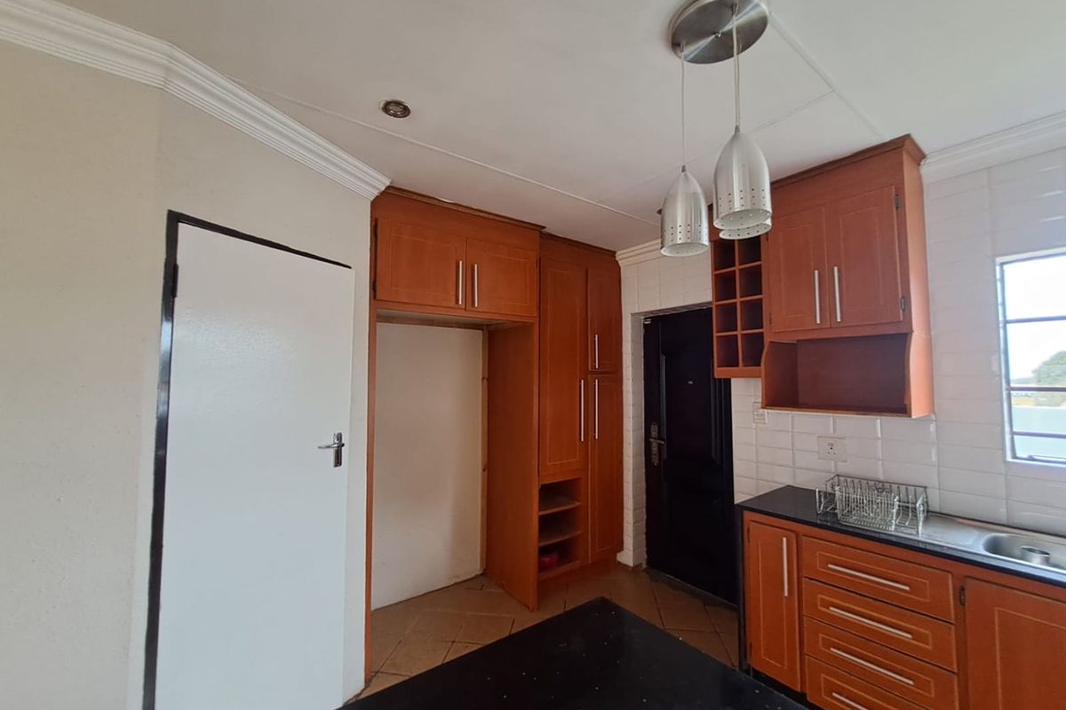A functional kitchen featuring wooden cabinetry, tiled backsplash, and dark countertops, offering a practical layout with ample storage space.